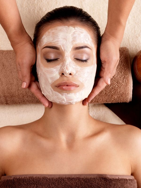 Woman receiving a facial treatment with cream on her face.