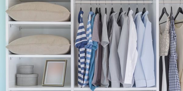 An organized closet with orderly shelves. Shirts are hanging with spaces in between them.