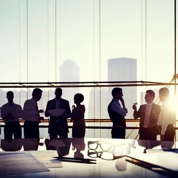 colleagues standing chatting in a meeting room with skyrise buildings in the background