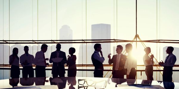 A group of people in front of a window in a business office with the city in the background