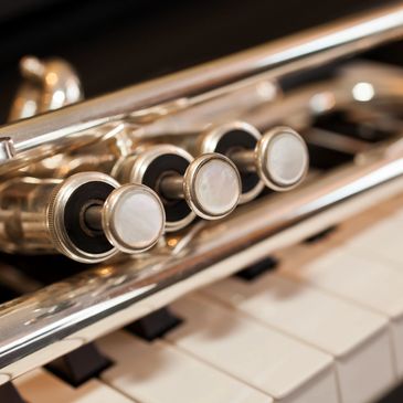 Close-up image of a trumpet on a piano keyboard.