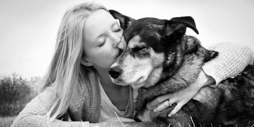 A woman kissing her black and tan dog outdoors
