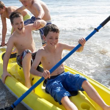 Boys enjoying kayaking at the beach on a sunny day.