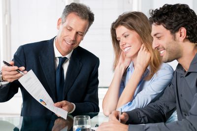 Professional representative reviewing material with happy husband and wife.