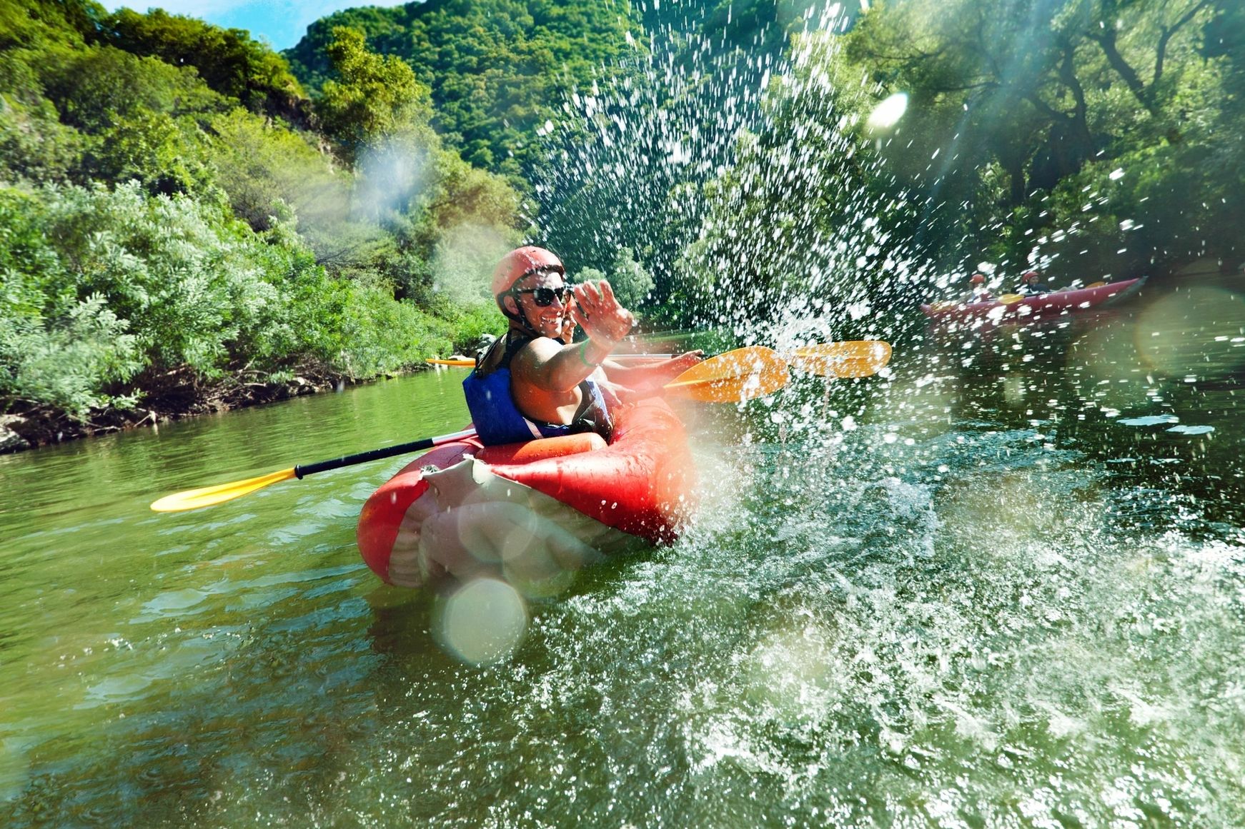 Man kayaking on the river splashing water at the camera