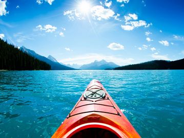 Kayaking on a bright, sunny lake surrounded by mountains.