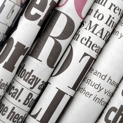 Close-up image of bundled up newspapers. Black newsprint letters on white newspaper.