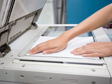 Hands placing paper on a photocopier glass.