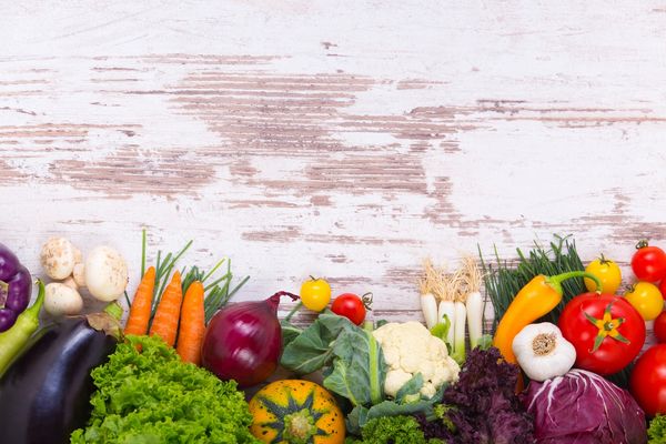 Fresh colorful vegetables arranged against a rustic white wooden background.