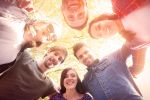 A group of friends smiling and standing in a circle outdoors.