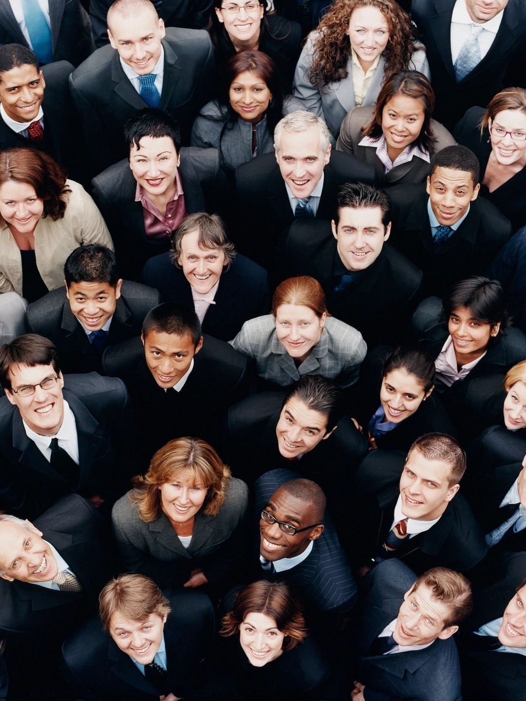 Group of diverse businesspeople smiling and looking up at the camera.