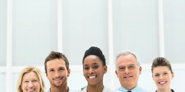 Group of five diverse professionals smiling.
