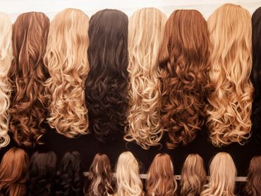 Various long, wavy hair extensions in different shades from blonde to brunette.