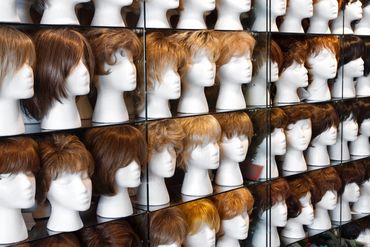 Mannequin heads with wigs on shelves in a store.