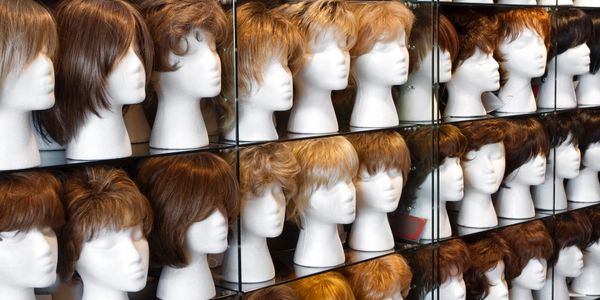 Rows of mannequin heads displaying various wigs in a shop.