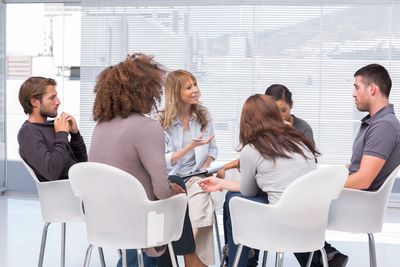 A group of people at an office sitting in a circle discussing something