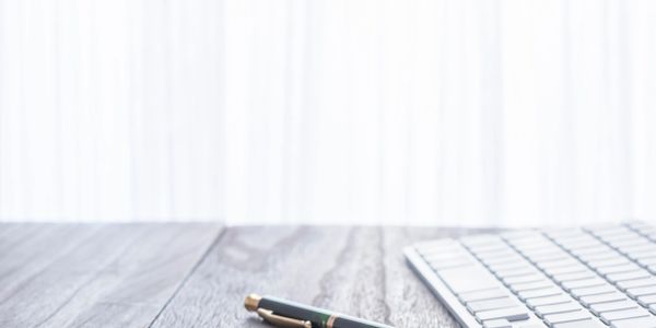 keyboard on a table with a pen