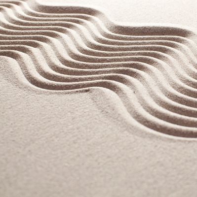 Smooth sand with artistic wavy patterns creating a calming effect.