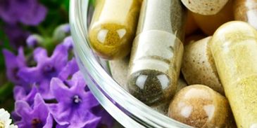 Close-up of herbal supplement capsules with purple flowers.