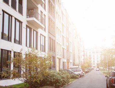 Apartment building on street filled with parked cars.