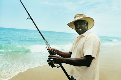 Man fishing on a beach with a big smile.