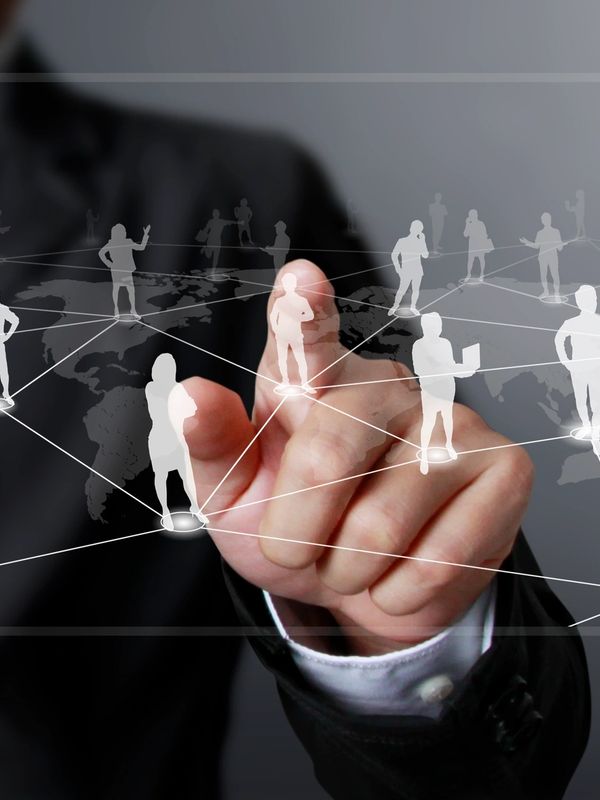 Hand interacting with a virtual network of connected people icons on a digital world map.