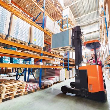 A reach truck busy loading cargo onto a rack in a warehouse. Safety Courses online