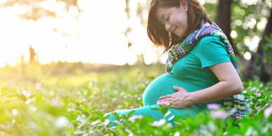 A pregnant woman sitting on the grass 