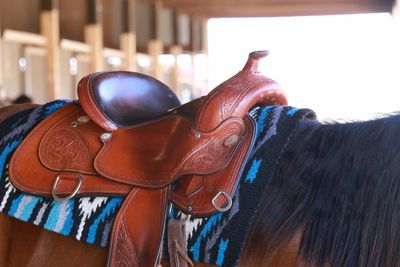 Close-up of a brown leather saddle on a horse with a colorful blanket.