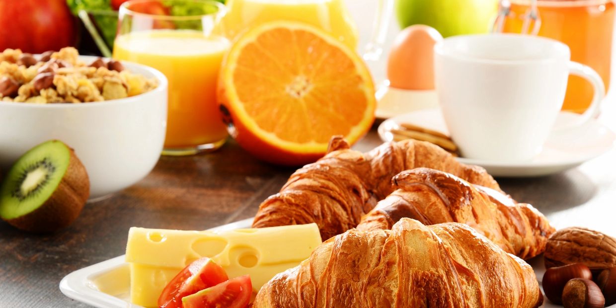 A delicious breakfast spread with croissants, cheese, fruit, and juice.