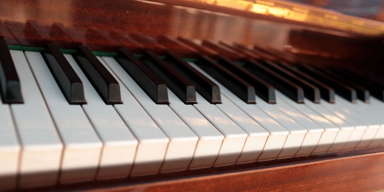 Close-up of piano keys with wooden frame and warm lighting.
