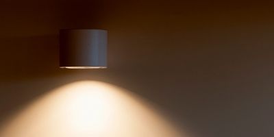 Wall-mounted light casting warm light on a plain wall.