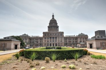 The Texas State Capitol building under a cloudy sky.