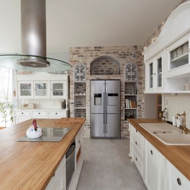 Bright rustic kitchen with wooden countertops and stainless steel refrigerator.