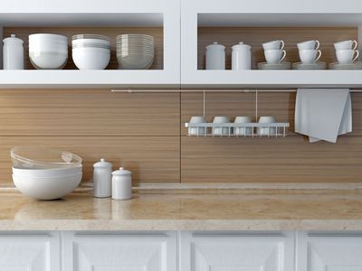 Minimalist kitchen shelf with white bowls, cups, and a towel on gray wall.