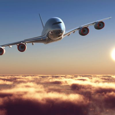 Airplane flying above clouds during sunset.