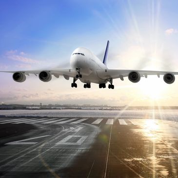 Large airplane landing on a wet runway during sunset.
