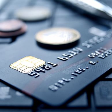 Close-up of a credit card chip and embossed numbers on a black card.