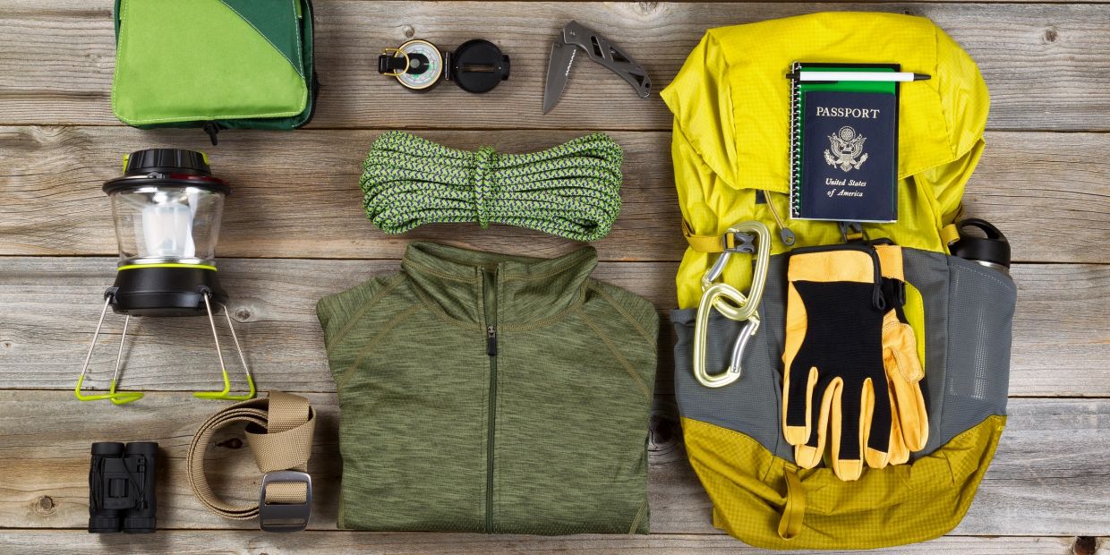 Hiking gear neatly arranged including backpack, gloves, and rope.