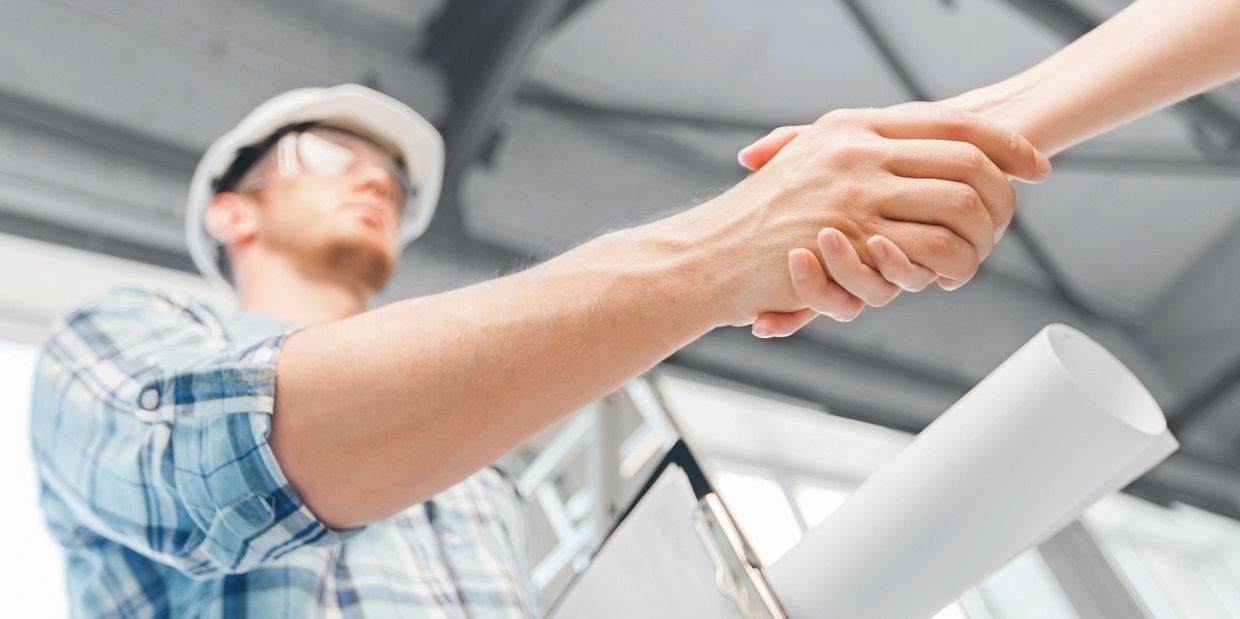 Construction worker shaking hands with client.