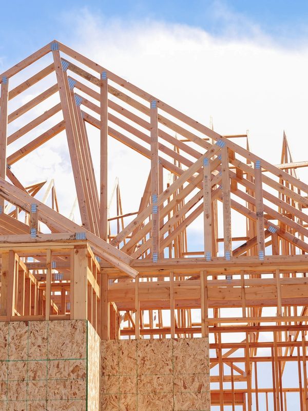 A building under construction with wooden beams and roof.