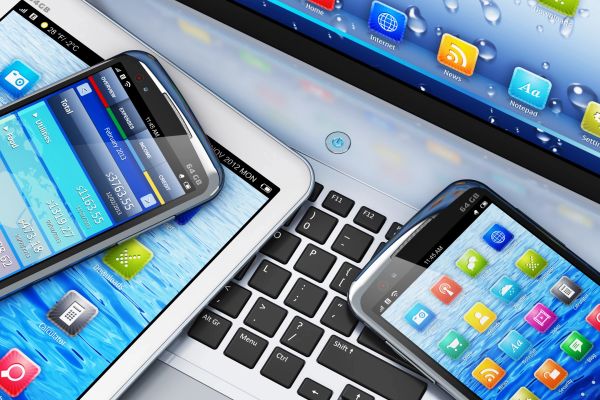 Two smartphones and one tablet on a laptop keyboard.