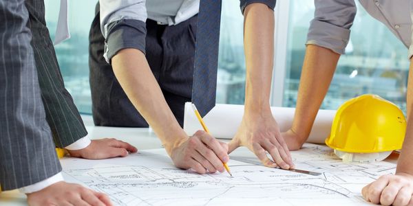 Three men discussing a set of construction plans on a table.