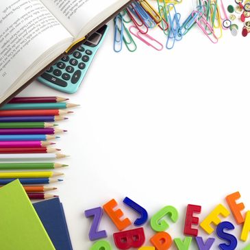 Colorful school supplies including pencils, letters, and calculator around an open book.