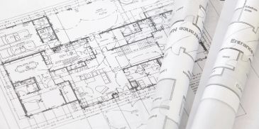 Architectural blueprints and rolled plans on a table.