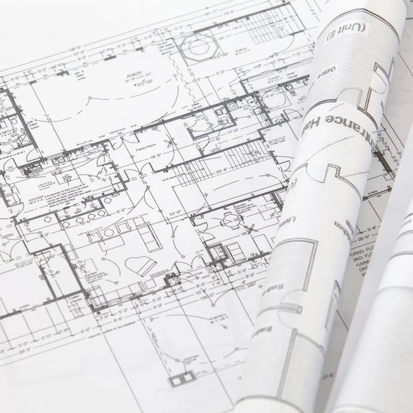 Detailed architectural floor plans and rolled blueprints on a table.