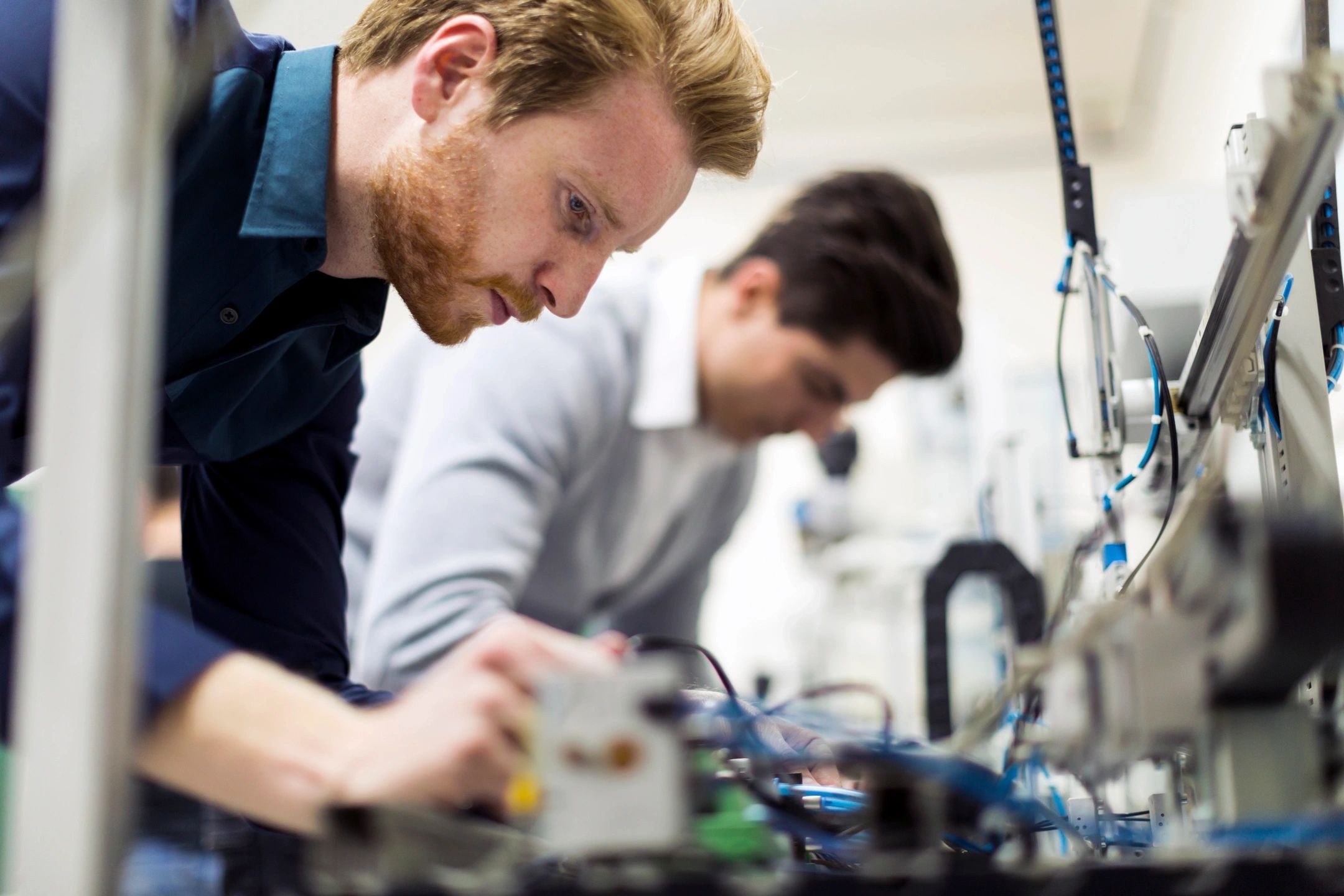 Two engineers working on a complex automation system, adjusting components on a test bench.