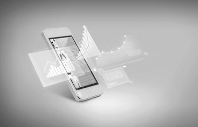 Smartphone displaying floating digital charts and data analytics.