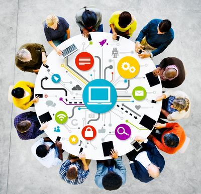 aerial view of workers sitting at round table, drawings of laptop in middle & work devices on table