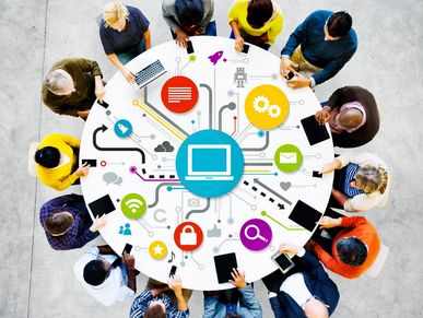 People collaborating around a digital network concept table with laptops and tablets.